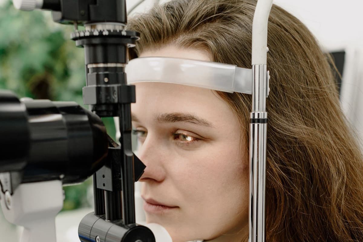 Žena naslonjena čelom na oslonac aparata dok se njeno oko pregleda na biomikroskopu