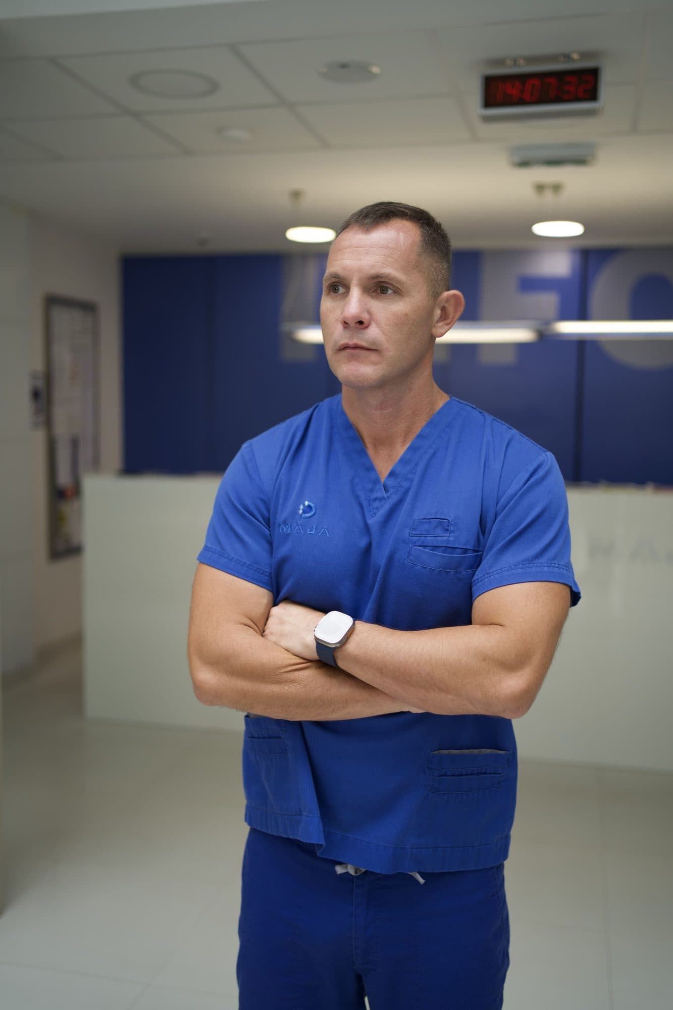 Doc. dr Marko Zlatanović u plavoj lekarskoj uniformi, prekrštenih ruku, u hodniku Klinike Maja