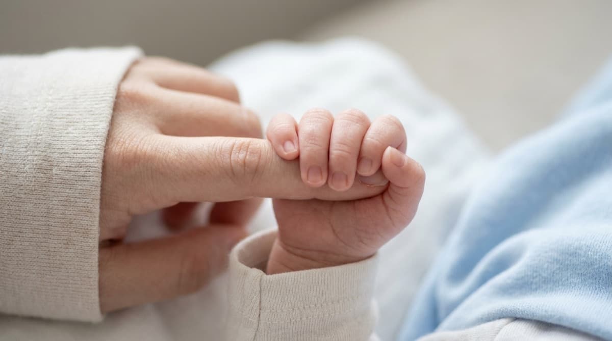 Bebina šaka obavijena oko prsta odrasle osobe